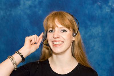 Close-up of beautiful businesswoman with headset against blue wall