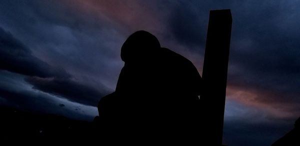 Low angle view of silhouette statue against dramatic sky