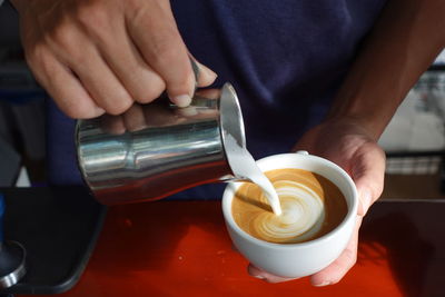 Midsection of man holding coffee on table