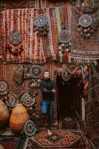 Full length of man standing against wall in market. turkish carpets