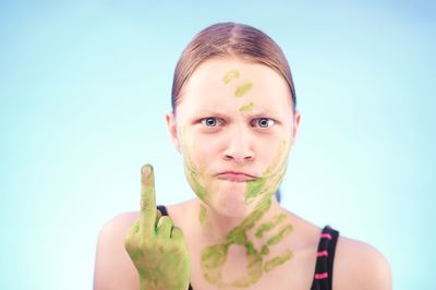 Aggressive woman showing middle finger against blue background