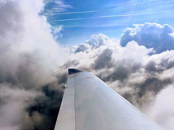 Low angle view of airplane wing against cloudy sky