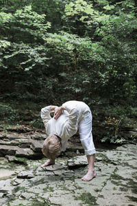 Senior woman doing yoga, bending over