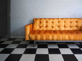 Golden sofa on tiled floor against brick wall at home