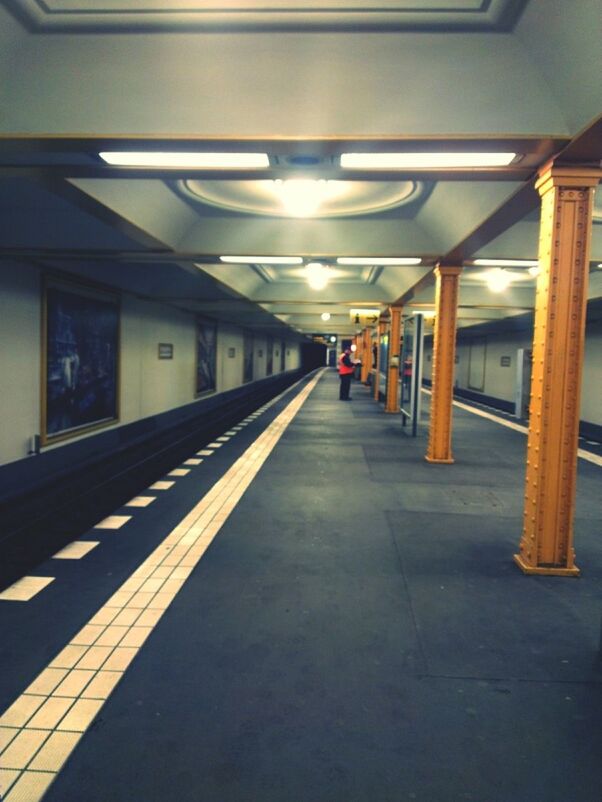 illuminated, the way forward, indoors, architecture, built structure, diminishing perspective, railroad station platform, transportation, railroad station, empty, lighting equipment, ceiling, incidental people, vanishing point, corridor, subway, public transportation, long, architectural column, subway station