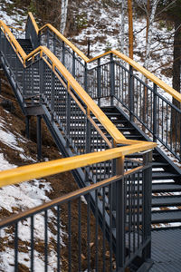Black metal staircase with wooden railing in the forest. trekking mountain route.