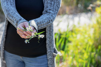 Midsection of woman holding flower