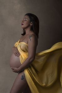 Pregnant woman standing against brown background