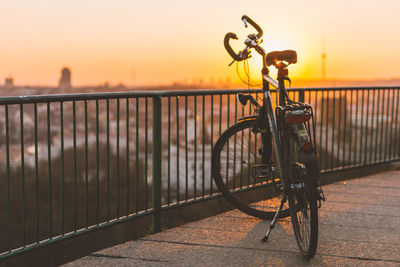 Bicycle at observation point against sky during sunset