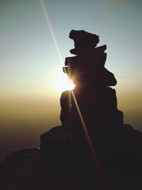 Silhouette statue of rock against sky during sunset