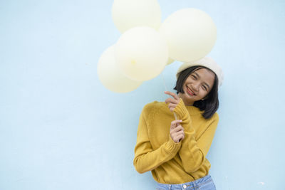 Young woman holding balloons against white background