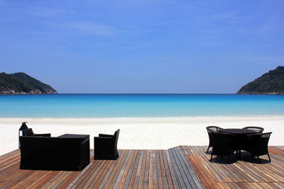 Furniture at beach against clear blue sky