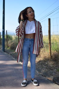 Full length portrait of teenage girl standing against sky