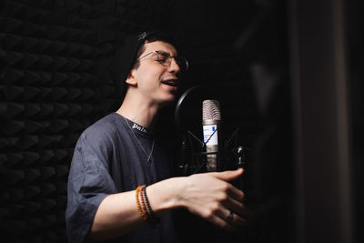 Man sings into microphone, professional recording studio, headphones. black soft walls, 