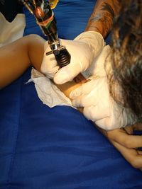 Cropped image of artist making tattoo on customer hand at studio