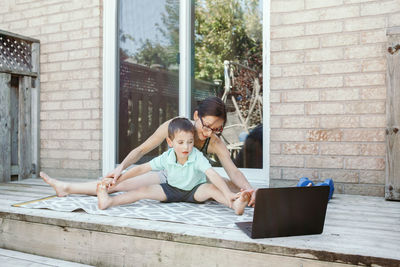 Family sport activity. middle age mother with toddler son doing distant online fitness workout 