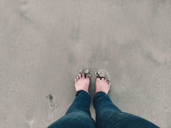 Low section of man standing on sand