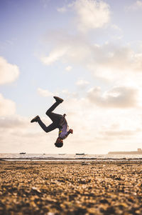 Low angle view of man jumping on beach