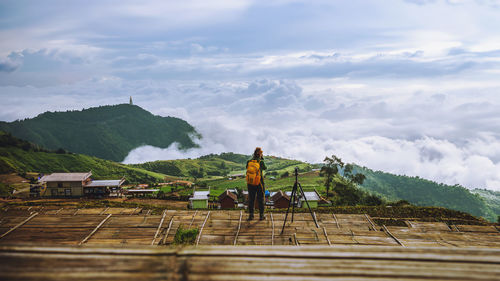 Rear view of man walking on mountain against sky