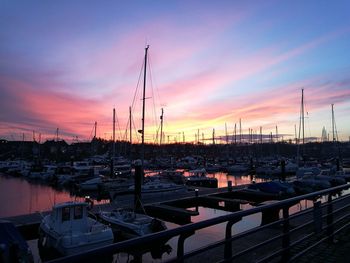 Boats moored at harbor against sky during sunset