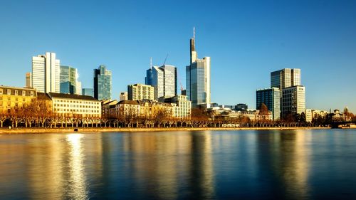 River by modern buildings against clear sky in city