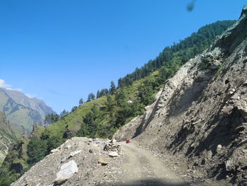 Road passing through mountains against clear blue sky