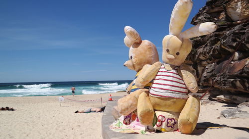 Stuffed toy on beach against sky