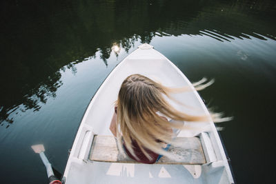 Rear view of woman sitting on boat in lake