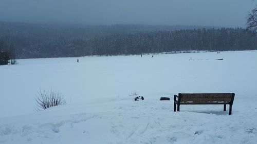 Empty bench on snow covered field during winter