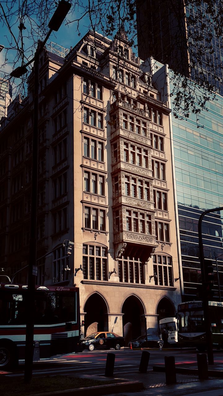 architecture, building exterior, built structure, city, urban area, downtown, street, building, transportation, mode of transportation, cityscape, evening, landmark, motor vehicle, car, road, city life, tree, night, nature, city street, land vehicle, sky, metropolis, travel destinations, neighbourhood, outdoors, skyscraper, facade, residential district, low angle view, window, office building exterior, metropolitan area