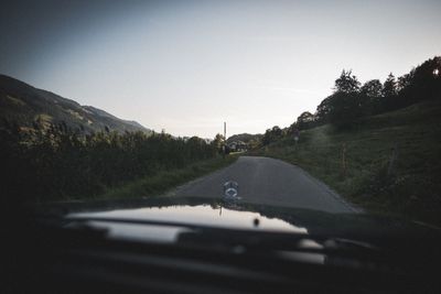 Road amidst trees seen through car windshield