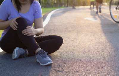 Low section of woman sitting on road