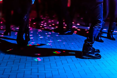 Low section of people dancing on illuminated floor