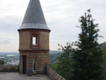 Tower amidst trees and buildings against sky