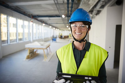 Portrait of smiling female engineer in protective workwear at construction site