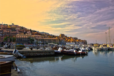 Boats moored in harbor at sunset