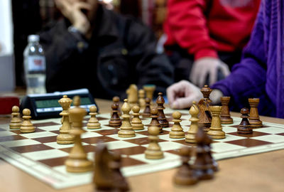 Midsection of people playing chess at home
