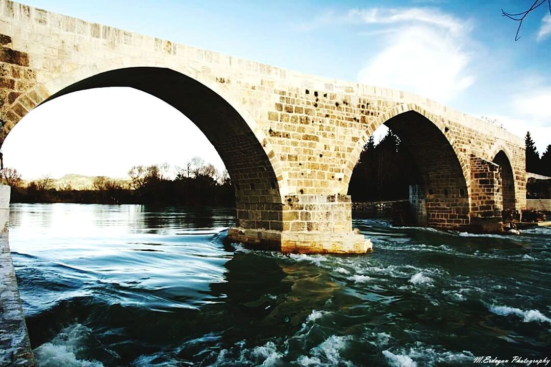 architecture, built structure, arch, connection, water, bridge - man made structure, arch bridge, river, building exterior, sky, bridge, waterfront, engineering, reflection, history, sunlight, famous place, city, architectural column, travel destinations