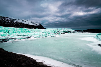 Icelandic glacier with basaltic surrounding and snow frozen lake 