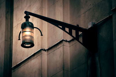 Low angle view of illuminated light bulb hanging on wall