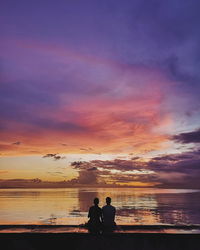 People on beach against sky during sunset