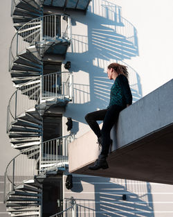 Low angle view of woman sitting against building