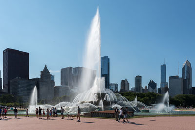 People on fountain against buildings in city