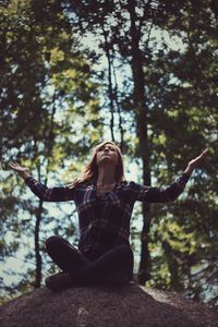 Woman sitting on rock in forest