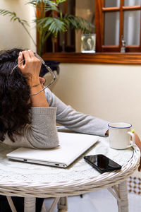 Side view of woman reading book while sitting at table