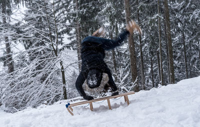 Full length of woman jumping on snow covered landscape