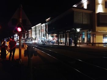 Illuminated railroad tracks on city street at night