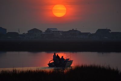 People on boat against orange sky