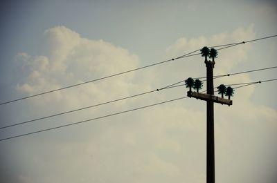 Low angle view of power lines against cloudy sky