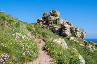 Stone wall on land against clear blue sky